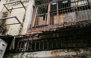 Fasad berjendela dengan jeruji, plester mengelupas, dan rel berkarat, dari Behind Jalan Besar’s Doors oleh Hidden Heritage dalam hidden gems Singapura