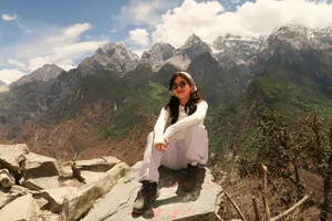 Solo traveller posing on rocky steps with dramatic mountain views in Tiger Leaping Gorge, Lijiang, during the 2D1N high trail