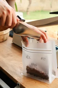 Hands sealing labelled coffee sample bags on a wooden table during packing at Seeker Yunnan Coffee Estate in Lijiang