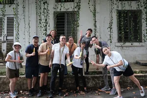 Team adventure group posing outdoors at Fort Serapong in Singapore, smiling with drinks in hand in front of a vine-covered wall