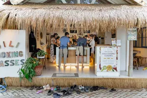 Thatched-roof entrance of Gili Cooking Classes on Gili T, Lombok, with signage and people waiting for the cooking class