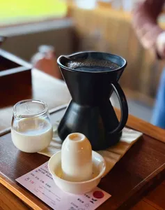 Black pour-over coffee setup with small glass tasting cups on a tray at Seeker Yunnan Coffee Estate workshop in Lijiang