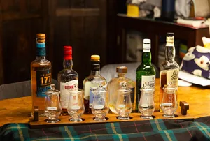 Row of whisky bottles and small tumbler glasses on a tray at a hidden home bar in Katong, Singapore, ready for small-batch tasting