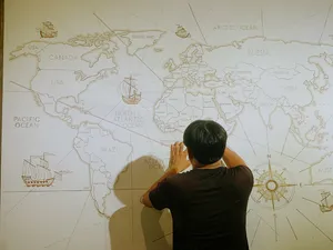 Seseorang menunjuk peta dunia di dinding saat sesi tradisi bagan kelahiran Vietnam di Chan Dat Living Room, Hoi An