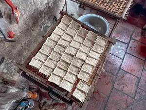 Tofu blocks draining on bamboo racks in a Hanoi workshop kitchen, photographed during a traditional low-waste tofu-making session