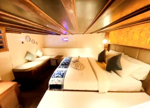Deluxe Phinisi cabin with neatly made beds for restful nights on a 4D3N shared Komodo cruise based in Labuan Bajo