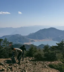 Hiker pauses on the rocky trail on Jade Dragon Snow Mountain near Lijiang, gazing over misty mountain valleys
