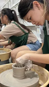 Pottery wheel lesson at 3Arts Pottery in Joo Chiat Place, Singapore, as students shape clay in green aprons — workshops in Singapore