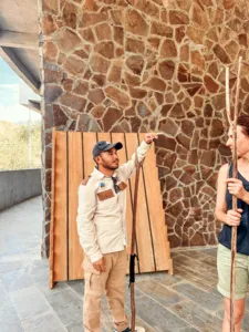 La Famille crew member holding a wooden door panel against a stone wall in Labuan Bajo, ready to welcome you on Komodo Island