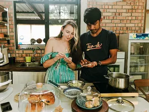 Farmhouse cooking lesson in Langkawi as two guests prepare Malaysian comfort food with herbs and pots in a brick kitchen