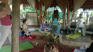 Meditation circle under a pavilion at Omunity Bali in Bali, with participants seated on mats beside flower-and-incense offerings