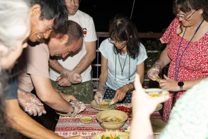 Guests at night on a cruise table wash and prepare seafood in bowls, sharing the evening meal during the Cat Ba experience