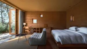 Kamar eco-retreat Linden Centre di Shaxi, Dali, dengan tempat tidur yang tertata rapi, dinding kayu, dan pintu terbuka ke area hijau