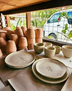 Inside Ilham Ceramic Studio in Langkawi, rows of unglazed cups and plates sit on shelves by large windows