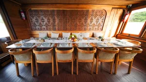 Banquet-style dining set with woven-back chairs on a phinisi cruise, ready for shared meals in Labuan Bajo