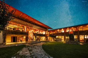 Starlit courtyard at Ferme Liotard in Shangri-La, with warm wooden verandas and a stone path for a Tibetan mountain valley stay