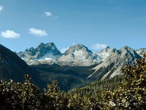 Snow-dusted mountain peaks and rugged ridges rising above forest on the Shangri-La hiking circuit for alpine lakes