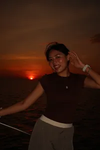 Seorang wanita tersenyum di atas dek ketika matahari terbenam di perairan terbuka semasa pelayaran kapal layar persendirian saat matahari terbenam selama 3 jam dari Kota Kinabalu, Sabah