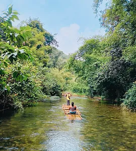 Raft on a calm river with passengers paddling through lush forest in Khao Lak, an adventure rafting moment