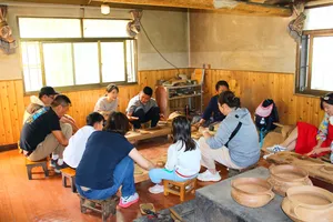 Travellers shaping clay in a wooden Tibetan pottery studio in Shangri-La, part of the Meet a Lama home lunch experience