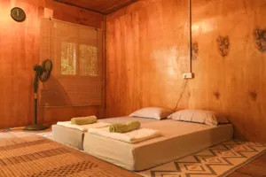 Cozy bedroom with a woven mat, pillows and wooden walls inside Ngapuh Homestead in Kuchingβs Bidayuh ancestral land