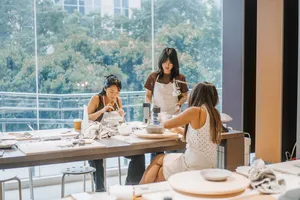 Pottery workshop in a Singapore ceramics studio, participants handcrafting antique European-style plates at worktables by large windows