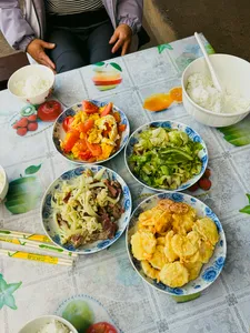 Naxi-style meal spread on a guesthouse table in Lijiang, with bowls of rice, vegetables, and stir-fry for the 2D1N trek