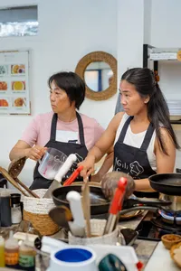 Two cooks in aprons measure and prepare ingredients at a Gili T cooking class in Lombok kitchen, focused and attentive
