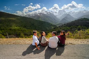 Travellers taking a break at a mountain overlook above Shangri-La, facing valleys on a 6-day trek with a Tibetan guide