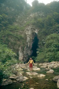 Woman standing in a shallow river with limestone cliffs and jungle in Phong Nha on a cave-and-fossils trip