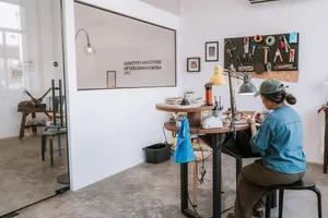 A jeweller seated at a workbench making rings at Fat Anvil Studios, with tools and equipment in their Singapore studio