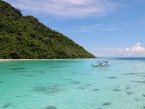 Bot yang berlabuh di teluk biru kehijauan di Semporna untuk pengalaman mendaki dan snorkeling Bohey Dulang & pulau-pulau bersama Bigfin Divers