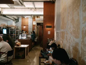Corridor-style restaurant interior with diners seated along the walls and an open service counter, in Joo Chiat, Singapore