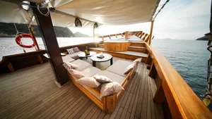 Angelica Liveaboard outdoor deck with cushioned sunbeds under a white canopy, cruising on a 3D2N luxe Komodo trip in Labuan Bajo