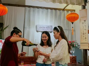 Tetamu di Chan Dat Living Room di Hoi An menuang dan merasa wain merah sambil tersenyum dengan gelas di tangan di dalam bilik yang diterangi tanglung
