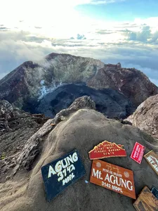 Mt Agung trail markers on rugged rock with cloud-filled valleys over Bali stretching into the distance during the sunrise trek