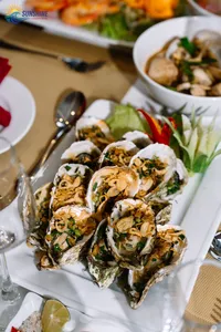 Grilled shellfish appetisers with herbs on white plates, served as part of dinner aboard a luxe 2D1N Cat Ba cruise