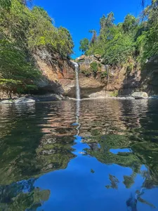 Waterfall spilling into a calm pool with reflections in Khao Yai National Park, shown during the trekking day trip