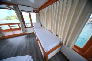 Cabin bed beside the side windows on a boat for a 3D2N join-in Komodo trip departing Labuan Bajo towards Komodo Island