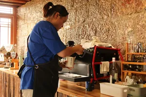Coffee roaster work at Seeker Yunnan Coffee Estate in Lijiang, with a family host tending the roasting machine