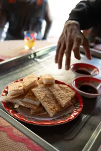 Sandwich bánh mì dengan saus cocolan di piring merah, disajikan saat singgah kuliner di Hoi An bersama Hoi An Backroad Tours