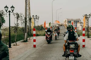 Pengendara berhelm mengikuti barisan skuter di jalan beraspal di Hoi An, bersiap berangkat untuk tur jalan belakang