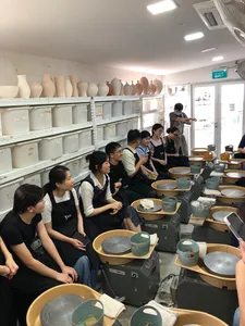 Sesi membentuk tembikar dengan roda putar di studio tembikar 3Arts di Singapura, pasukan kreatif duduk di roda tembikar untuk bengkel tembikar di Singapura