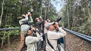 Travellers on an open observation boat scanning the jungle with binoculars during a wildlife-guided tour in Cat Tien, Vietnam