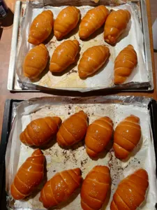 Golden shio pan rolls lined on baking trays at a The Daily Staples bread-making class in Singapore, ready to cool after baking
