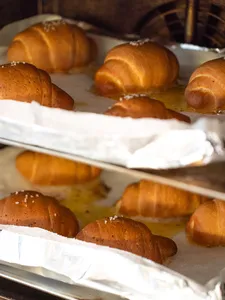 Golden shio pan buns cooling on lined trays on wooden racks inside the bakery for hands-on workshops in Singapore