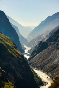 Ngarai sungai yang sempit di utara Yunnan, diapit gunung-ganang yang curam, dengan cahaya lembut menyinari lembah yang berliku
