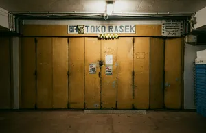 Pintu rolling toko yang tertutup di lorong beratap di pelabuhan Jurong, Singapura, dengan papan toko terlihat di atas deretan tempat sampah