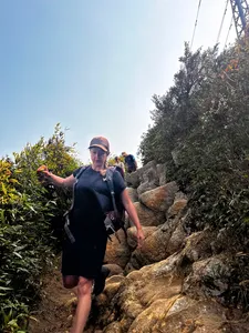 Sung A Chu leads an eco trek along a rocky forest path in Sapa, gesturing ahead while hiking towards Fansipan