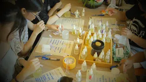 People at a shared bench in Singapore working with fragrance bottles and dropper tools during a coco-soy candle workshop